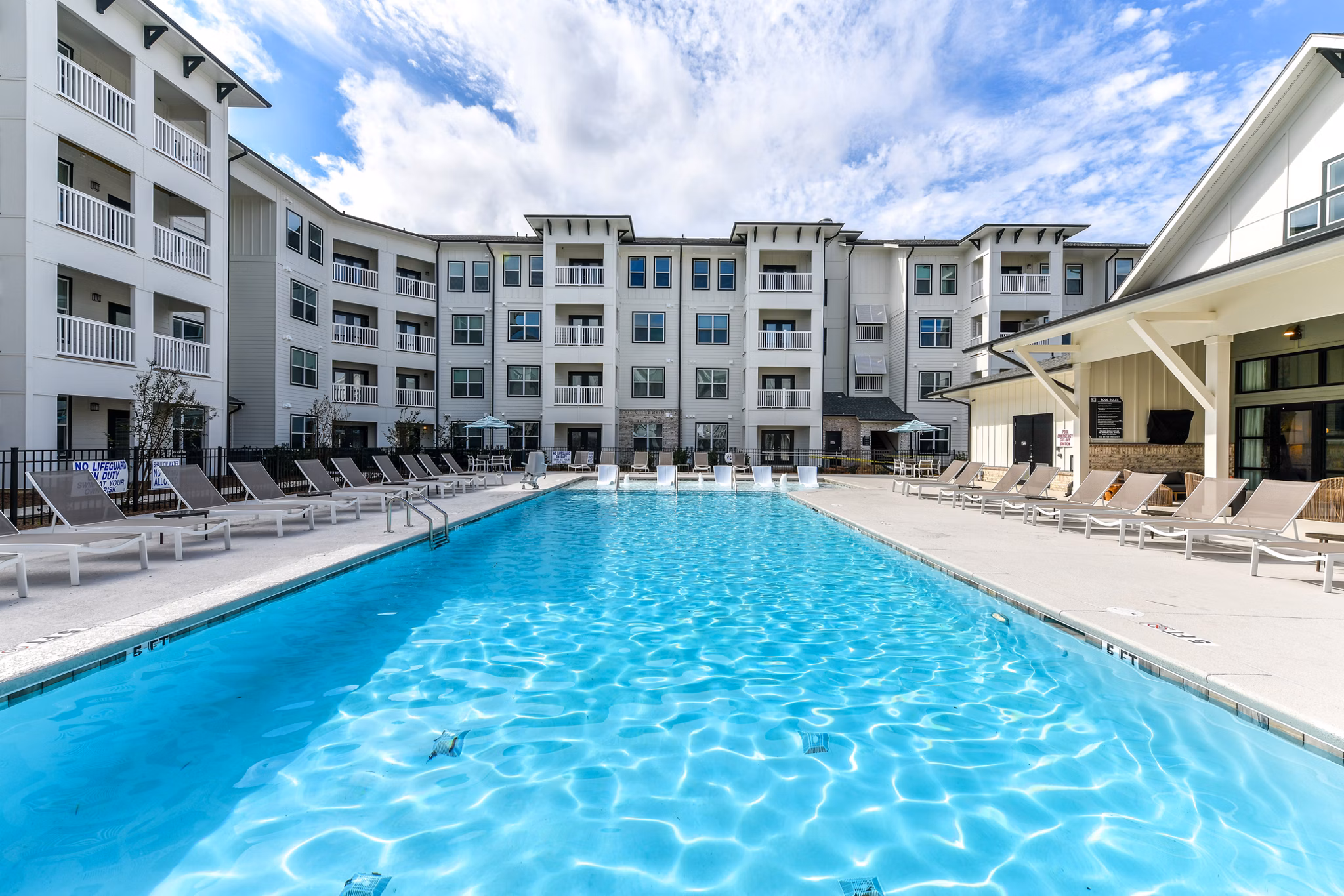 Relaxing poolside retreat at Highland Exchange Apartments with crystal clear water and luxurious lounge chairs