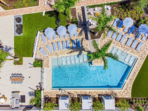 Serene lake view at Summerhouse Lakewood Ranch Apartments featuring lush greenery and outdoor seating areas