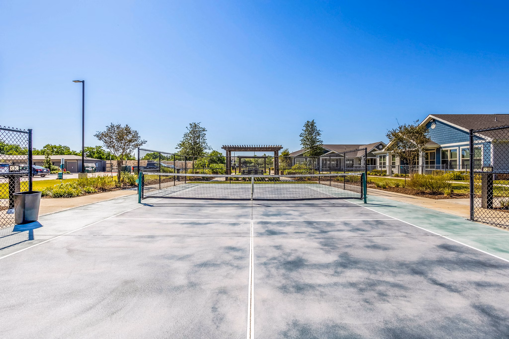 Outdoor tennis court at Larkspur at Shadow Creek Apartments surrounded by lush greenery