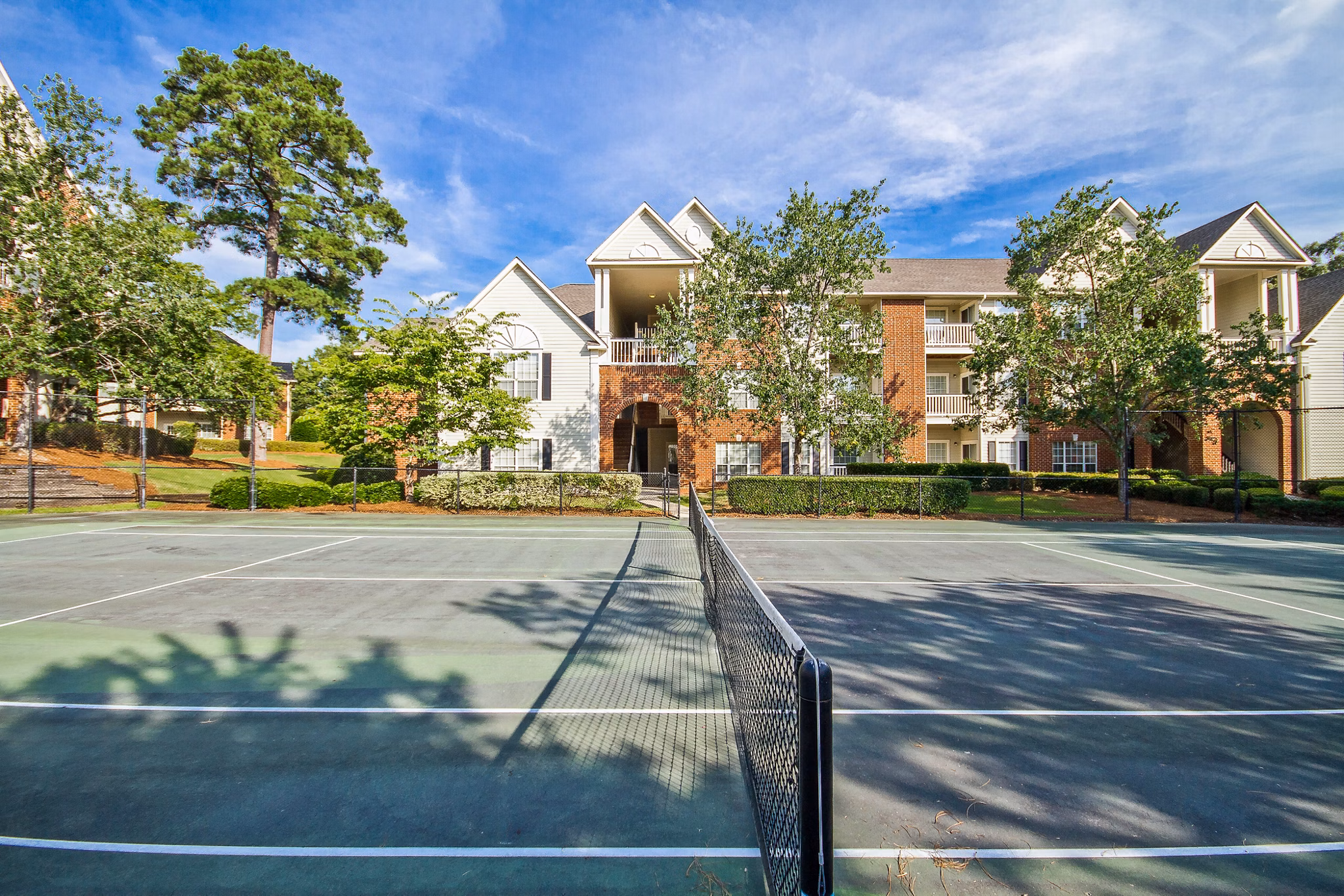 Outdoor tennis court with landscaped surroundings at 42 Magnolia and 5000 Forest Apartments
