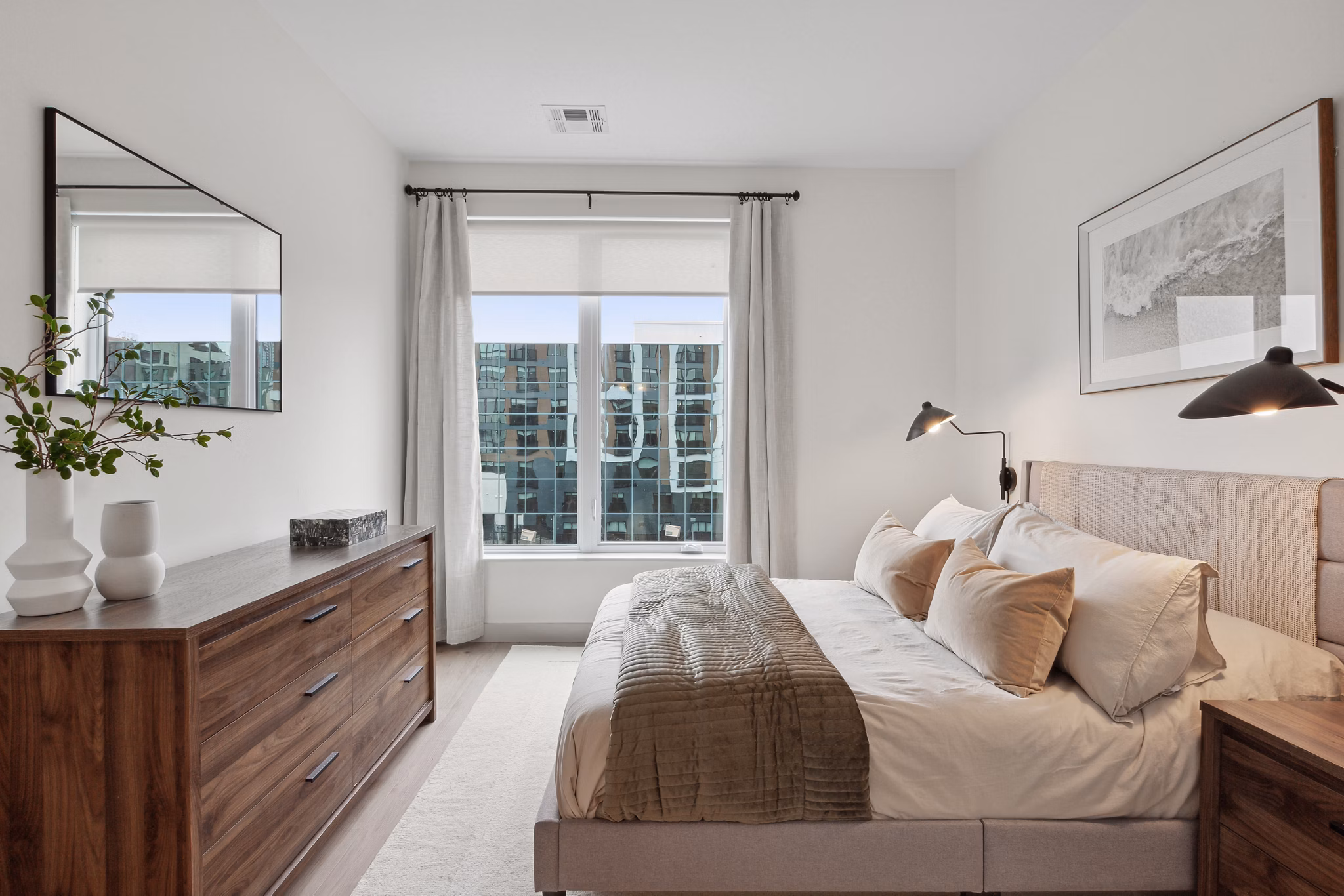 Cozy bedroom with modern decor and large windows at Motif Apartments