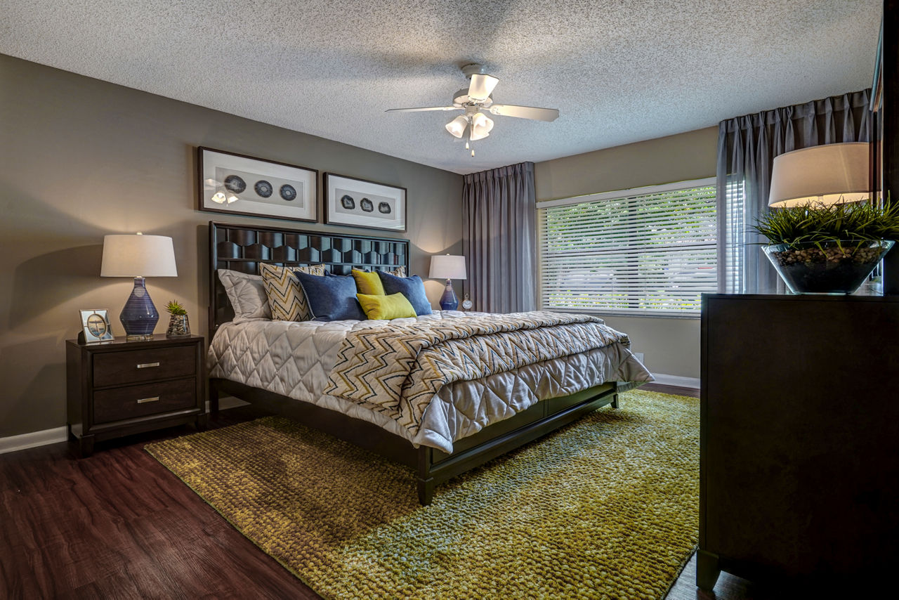 Stylish bedroom with large bed, modern lamps, and window view at The Plantation Colony Apartments in a luxury Greystar community