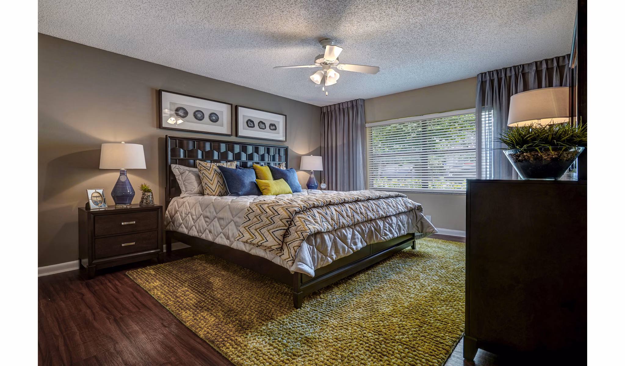 Stylish bedroom with large bed, modern lamps, and window view at The Plantation Colony Apartments in a luxury Greystar community