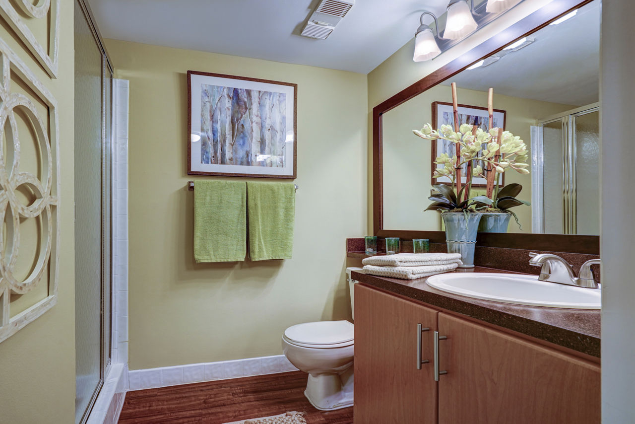 Modern bathroom with shower, vanity, framed art, and green towels in The Plantation Colony luxury apartments
