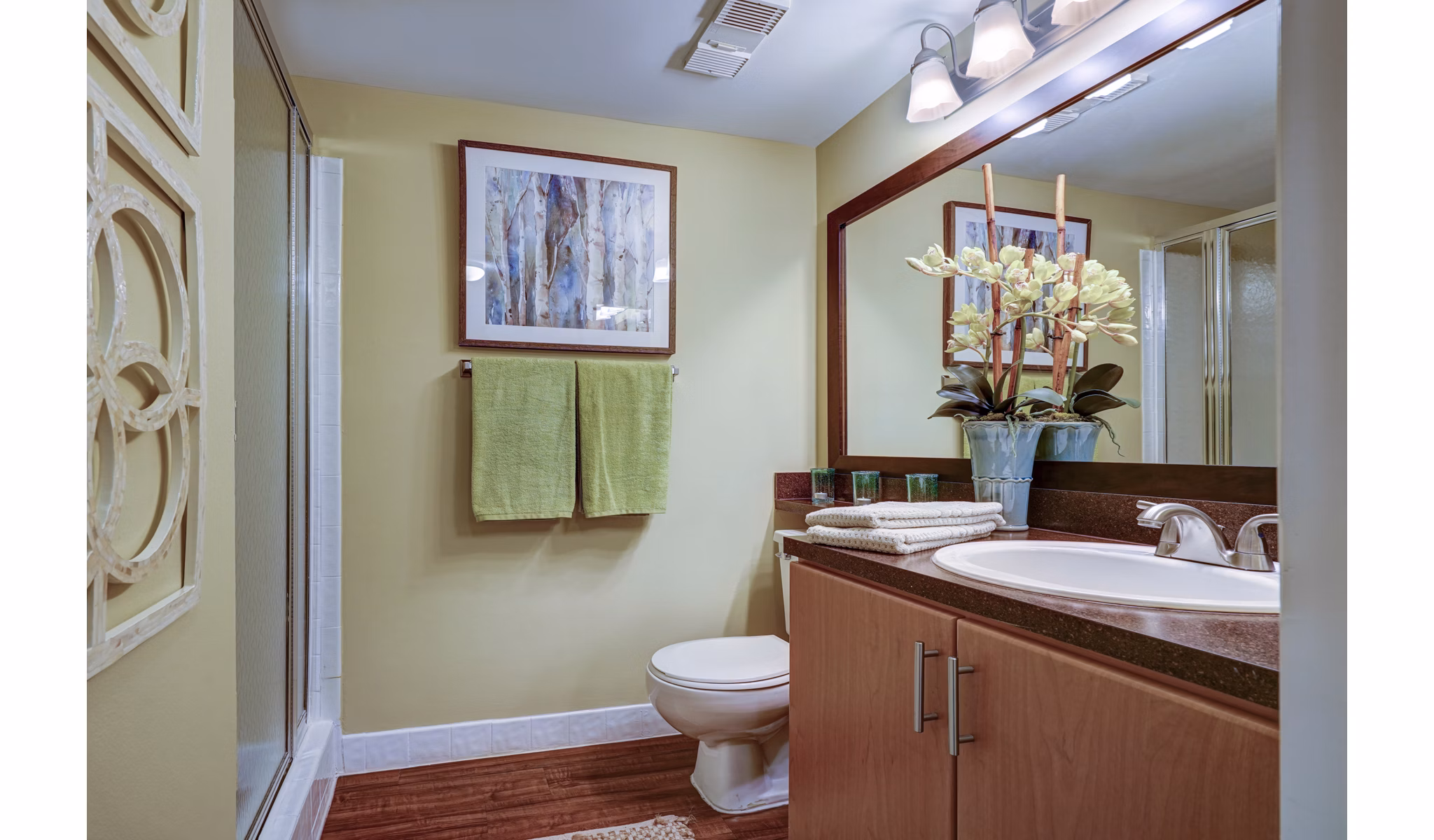 Modern bathroom with shower, vanity, framed art, and green towels in The Plantation Colony luxury apartments