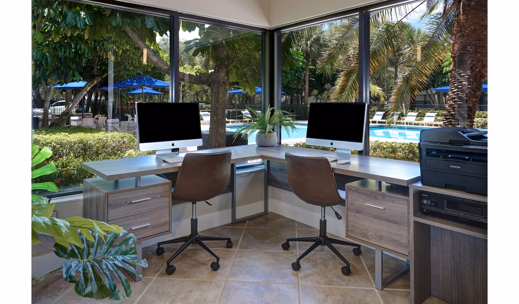 Two computer desks by large windows with pool view at The Plantation Colony Apartments