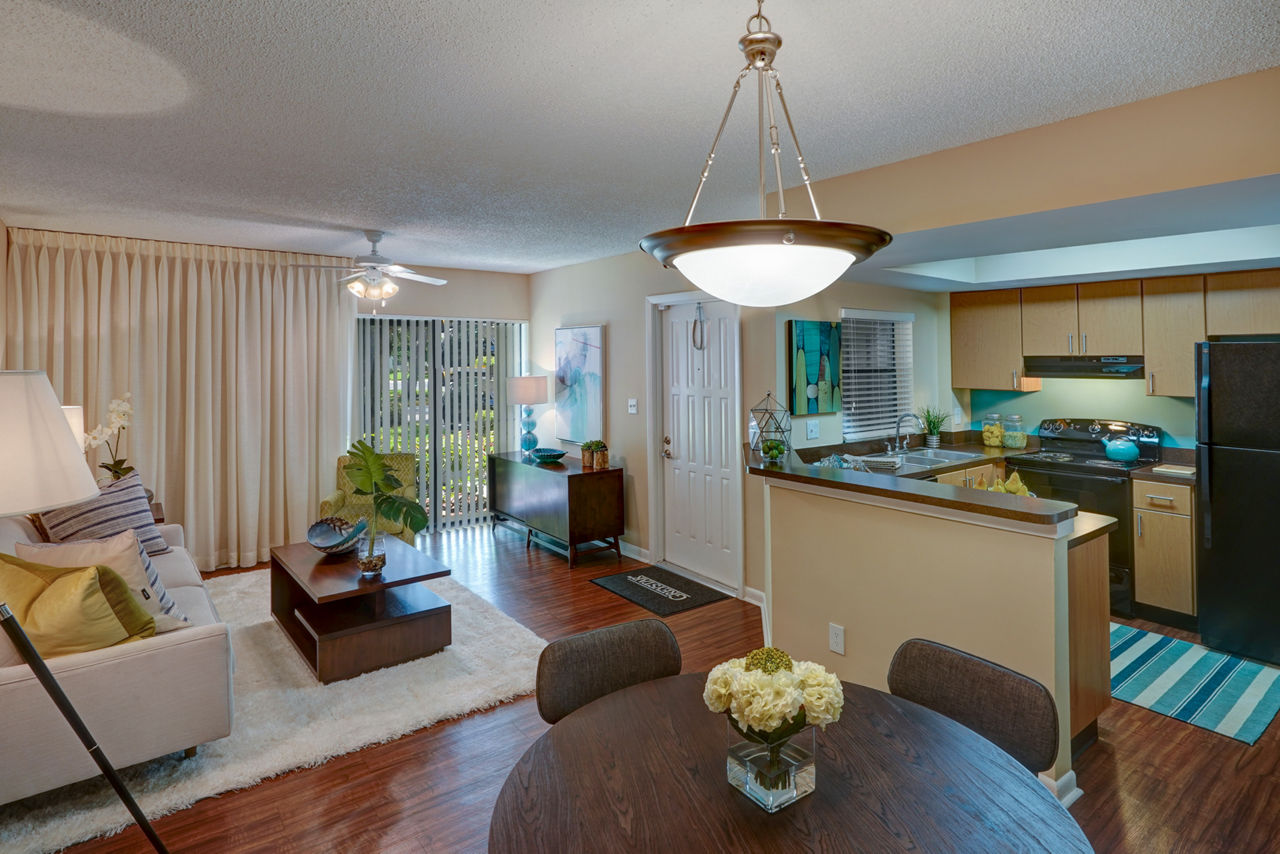 Open-concept living room and kitchen with modern decor and lighting at The Plantation Colony Apartments