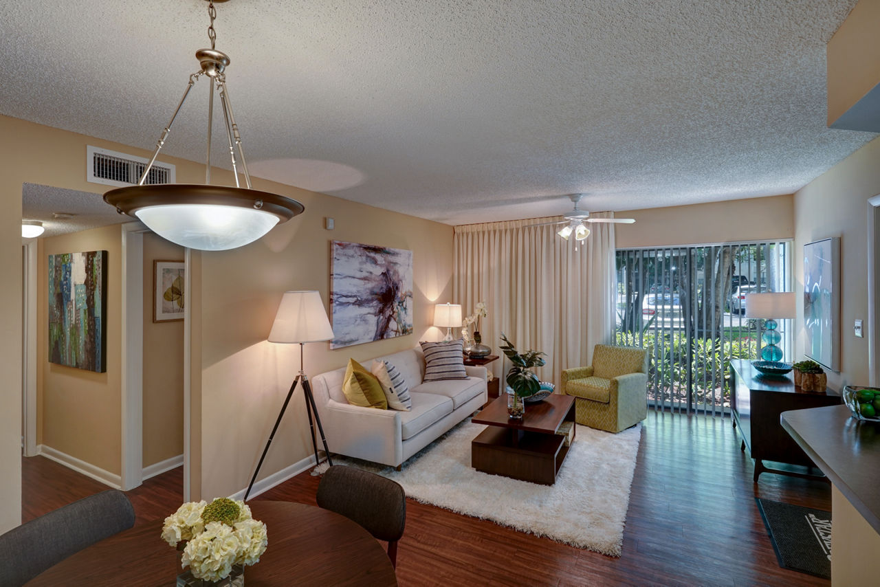Cozy living room with comfortable seating and a large window at The Plantation Colony Apartments, luxury living in Plantation, Florida