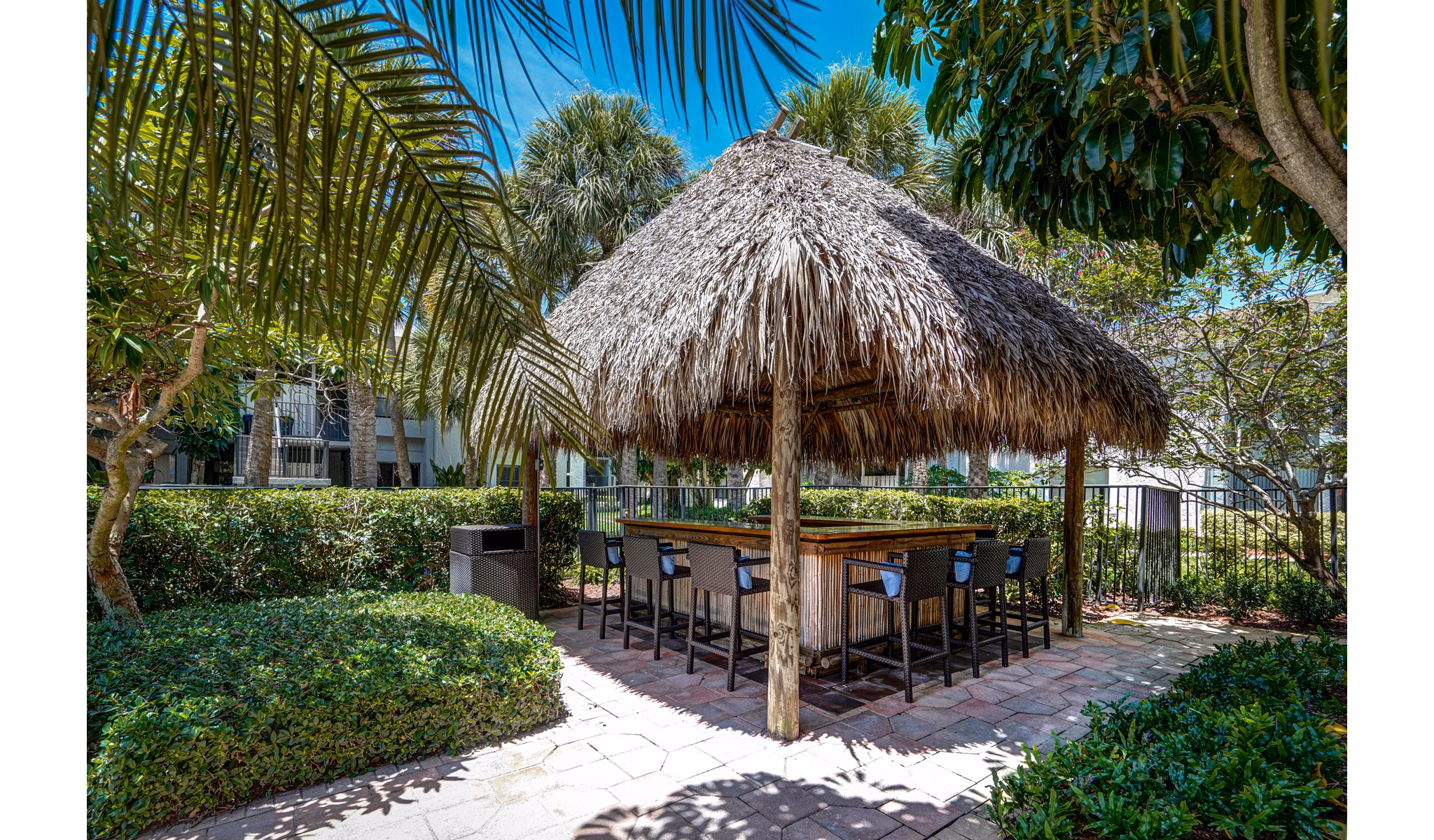 Outdoor tiki hut with bar seating surrounded by lush greenery at The Plantation Colony Apartments