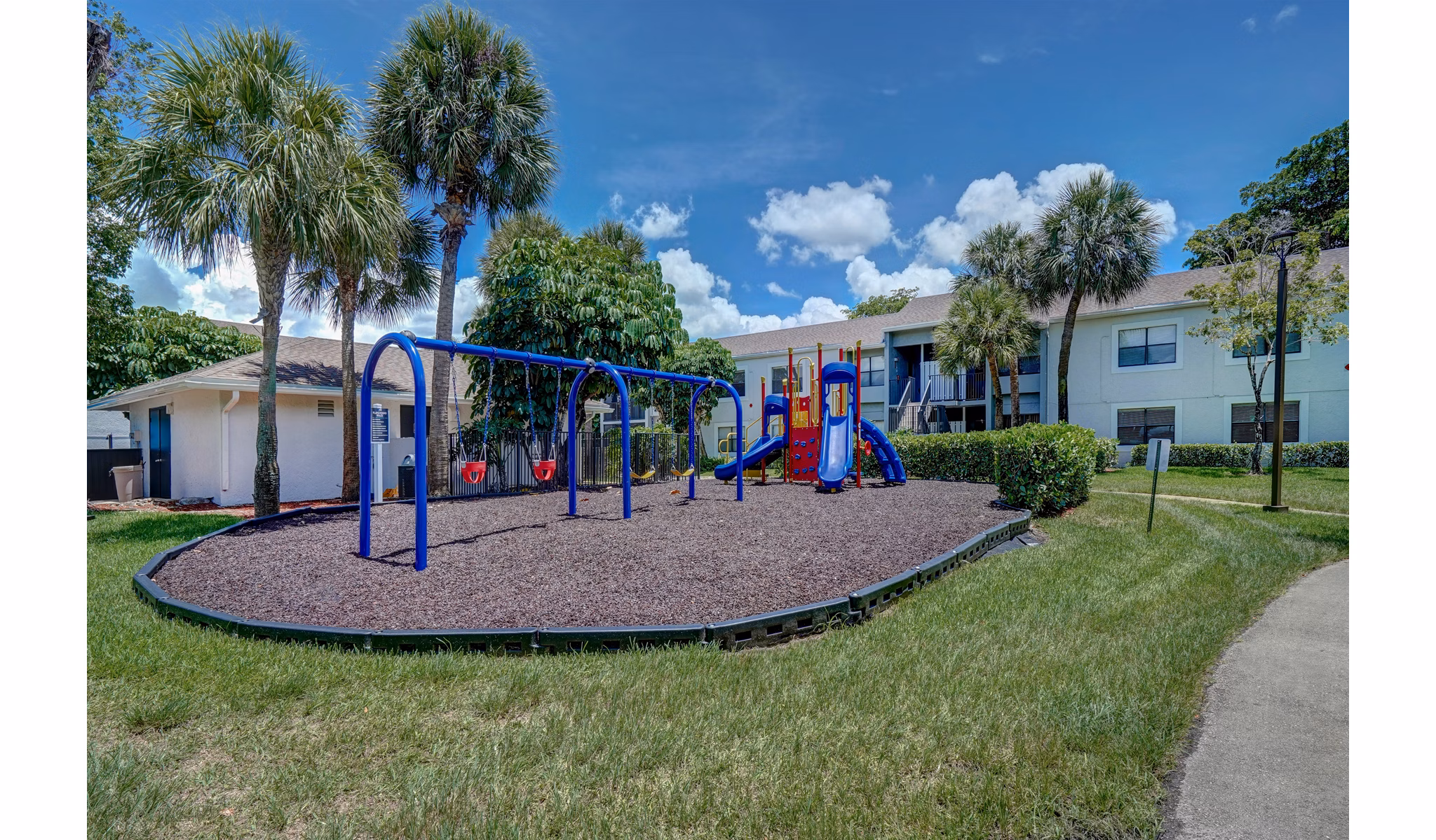 Playground with swings and slide in residential area at The Plantation Colony Apartments