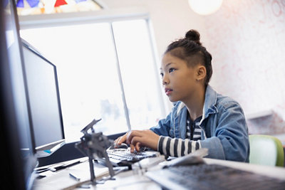 Young girl programming robotics at computer in classroom