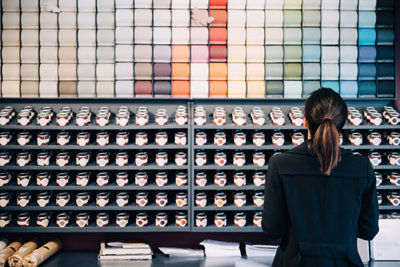 Woman choosing wallpapers and paints displayed for sale in store