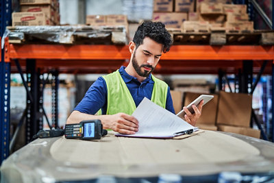 Young manual worker reading checklist in a warehouse