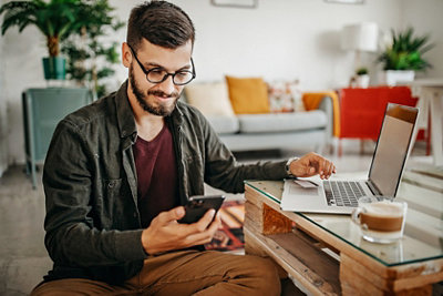 Men text messaging with smart phone, working from home
