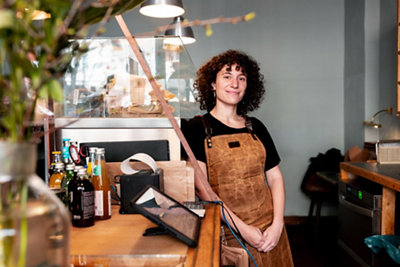 카메라를 향해 다정하게 웃고 있는 논바이너리 성별의 젊은 바리스타의 초상화