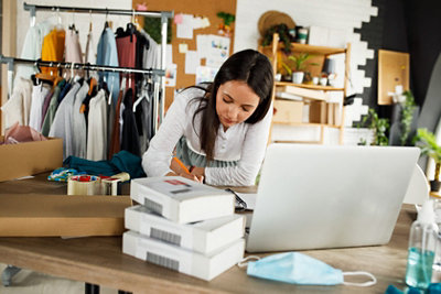 سيدة أعمال تتكئ على سطح العمل وتكتب في دفتر ملاحظاتها