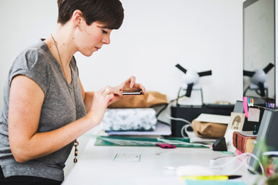 Young woman depositing check using smart phone in office