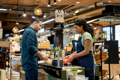 Latin American male customer shopping at the supermarket and checking out at the cash register